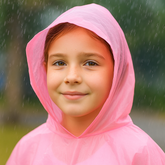 Kids Rain Poncho – Lightweight & Waterproof worn by a smiling girl in the rain, showcasing its waterproof features.