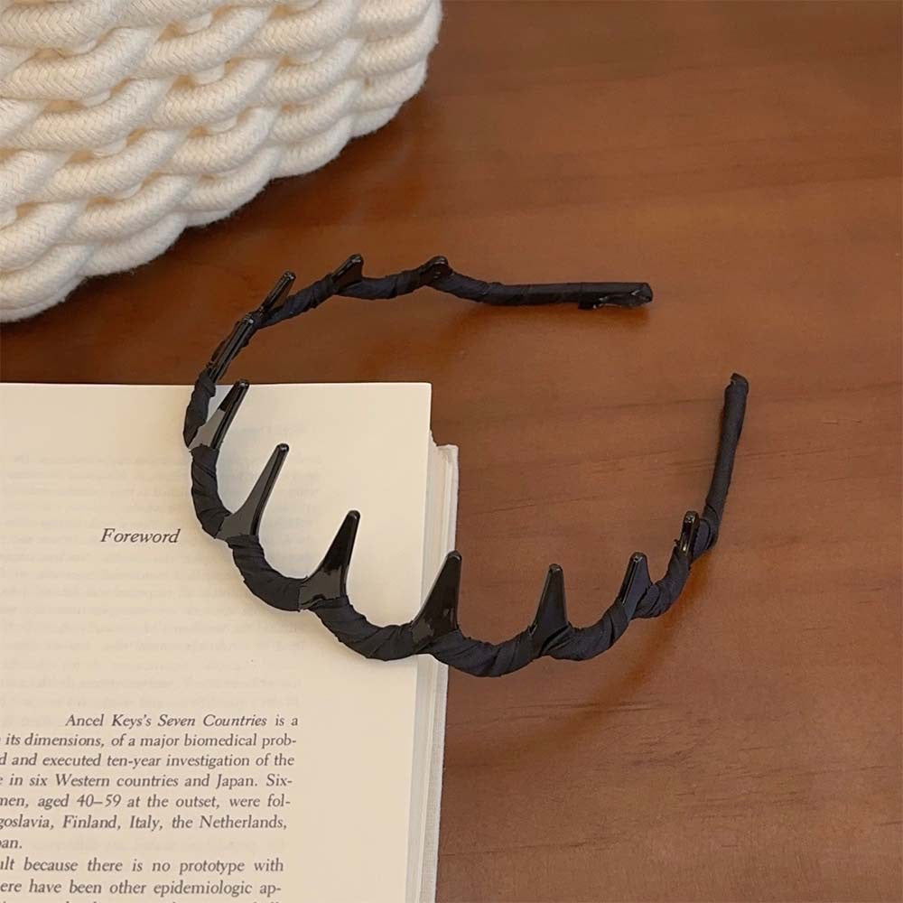 Zigzag Hair Band – Flexible Plastic Headband resting on a book, highlighting its durable black design.