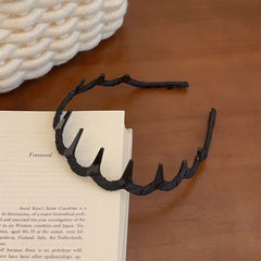 Zigzag Hair Band – Flexible Plastic Headband resting on a book, highlighting its durable black design.