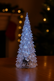 🎄 X-mas Flashing Tree (12.5CM) glowing acrylic Christmas tree on a table with a cozy holiday background.
