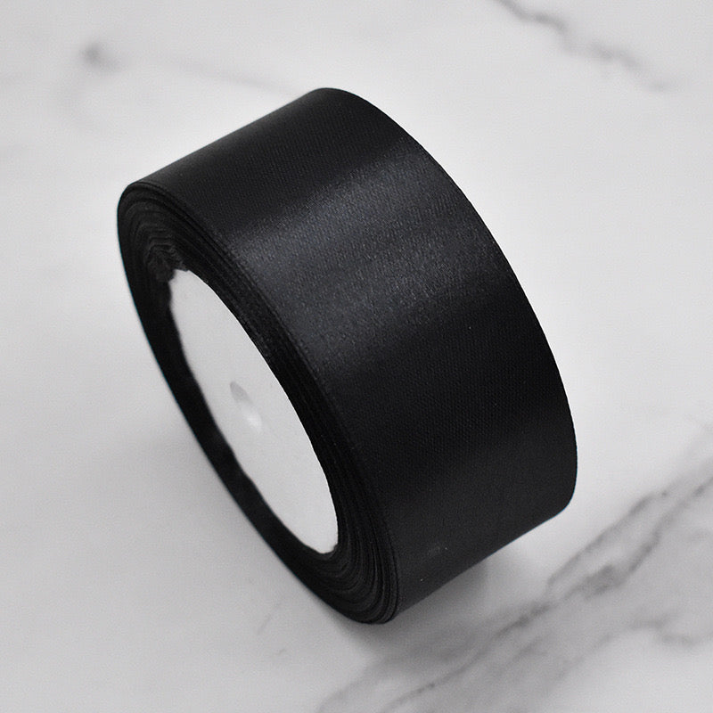 🧵 Premium Satin Ribbon – Versatile & Elegant, black satin ribbon roll on marble surface.
