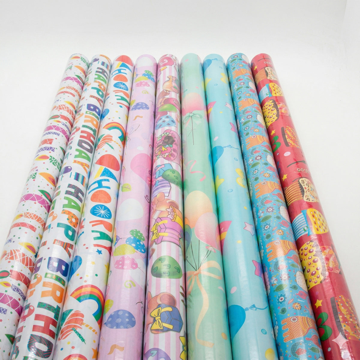 Rolls of colorful birthday-themed gift wrap paper on a white background