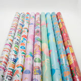 Rolls of colorful birthday-themed gift wrap paper on a white background